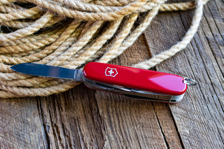 Army multipurpose pocket Swiss knife and ropes on an old wooden table.のeditorial素材