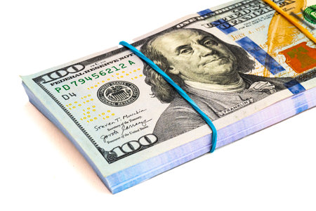 stack of US dollar bills tied with a rubber band. Cut on a white background.