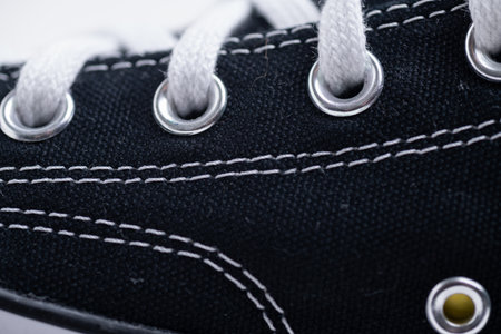 Close-up of white shoe laces on textured black sport shoes.