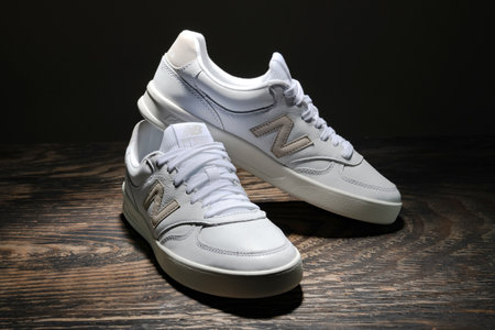 White leather New Balance sneakers on a dark wooden background.のeditorial素材