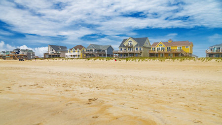 Blue sky over Atlantic beach, sand and Rows of beach houses on stilts in Avon, North Carolina.の写真素材
