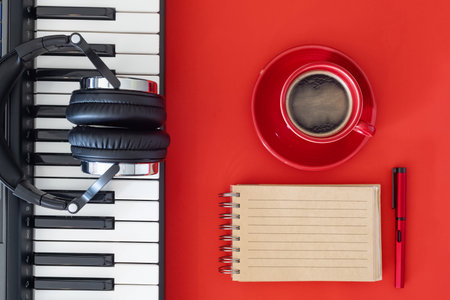 Home studio with headphones and keyboard. Red background minimalist setup.の写真素材