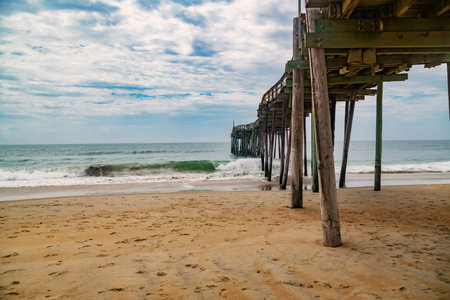 Rustic wooden jetty on wide shoreline. Cloudy summer sky over calm sea and empty coast.の写真素材