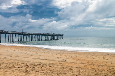 Wooden pier stretching into the Atlantic Ocean. Tranquil beach scene under blue sky with clouds.の写真素材