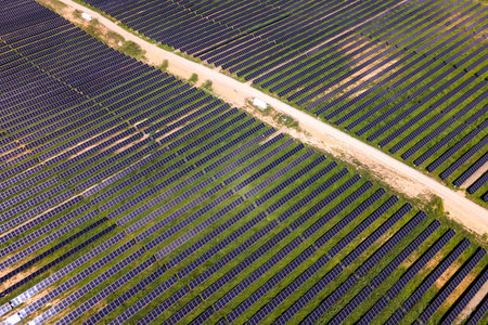 Aerial view of photovoltaic solar farm producing electricity for modern housing estate.