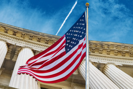 United States flag flies proudly on Washington government building, representing American...