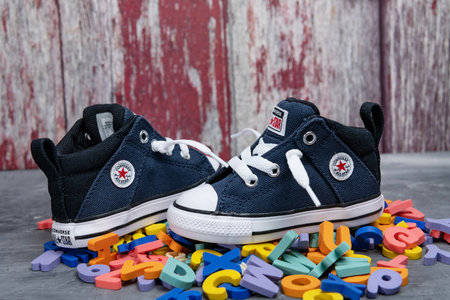 pair of CONVERSE sneakers for kids against a backdrop of colorful alphabet letters.