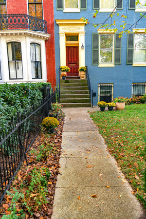 Colonial Style Residence With Red Door and Leaf-Covered Entry Path