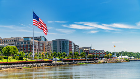 National Harbor waterfront with buildings and an American flag on the banks of the Patomak River.のeditorial素材