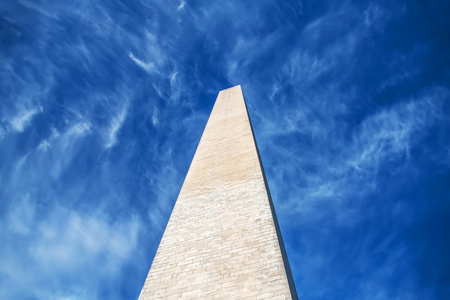 Low angle view of Washington Monument against vibrant blue sky with scattered white cloudsの写真素材