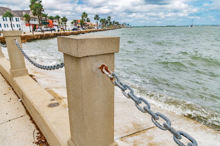 Concrete bollard with metal chain along coastal waterfront promenadeの写真素材