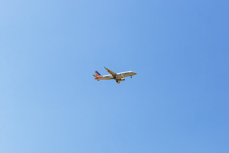 American Airlines passenger plane flying in blue sky with visible landing gear