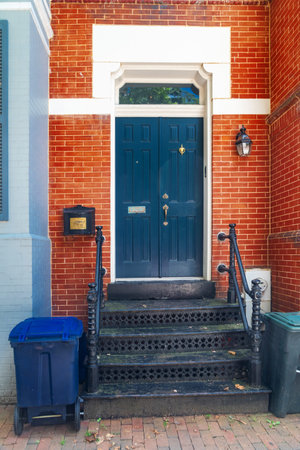 Brick townhouse entrance with iron staircase and wooden door in urban neighborhood