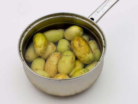 Scrubbed potatoes with skin for healthy eating in pan ready for boiling.の写真素材