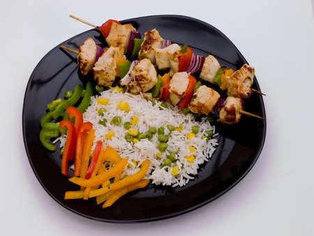 Grilled chicken on a black plate with rice.の写真素材