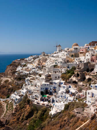 A vertical shot of the village of Oia in Santorini Greece that is well known for its collection of white washed terraced apartments climbing up the side of the rock face.の写真素材