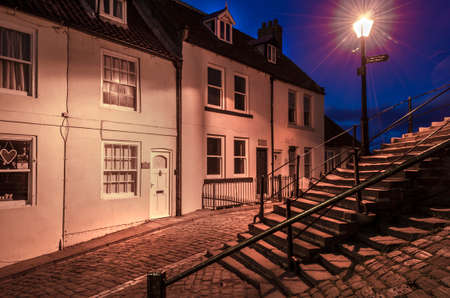Steps and cottages at dusk illuminated by a street lamp giving of an ethereal glow.の写真素材