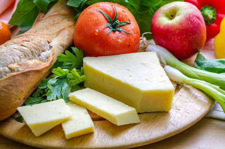 A horizontal shot of a delicious quick snack of a ploughmanâs lunch with French bread mature cheese a fresh tomato and an apple.の写真素材