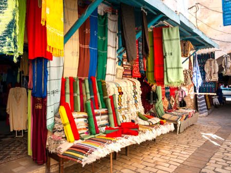 A shop in an Arabian bazaar where a wonderful collection of coloured clothes and materials for sale are displayed out side in the streetのeditorial素材