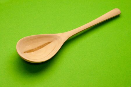 Wooden spoon isolated on green backgroundの写真素材