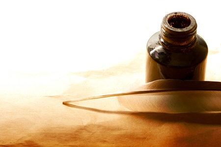 Feather and ink bottle isolated on paper background の写真素材