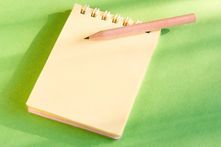 Notepad and pencil on the green backgroundの写真素材