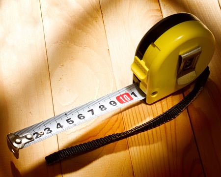 Tape measure isolated on wooden background 