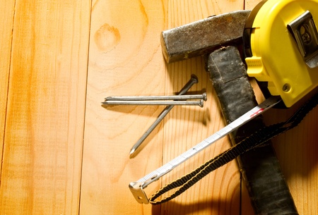 Hammer, tape measure and nails isolated on the wooden backgroundの写真素材