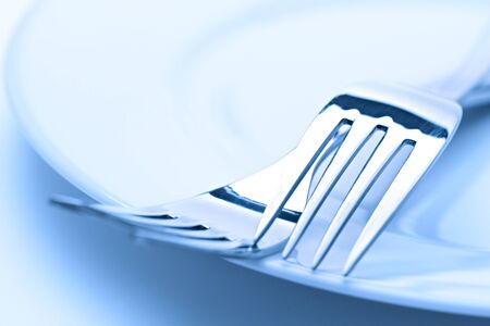 Two forks on a plate in blue light