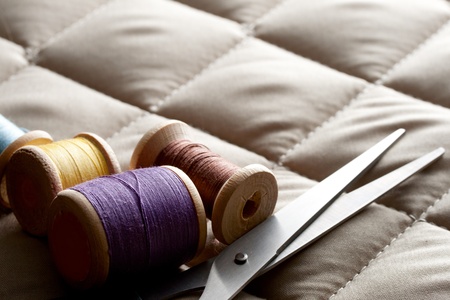 Thread bobbins with scissors on a gray fabricの写真素材