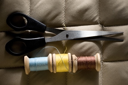 Thread bobbins with scissors on a gray fabric の写真素材