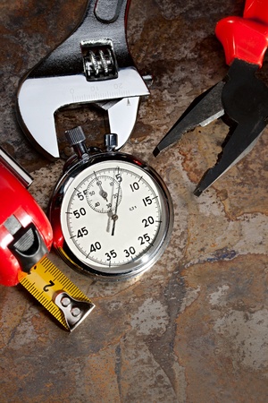 Spanner, pliers and stopwatch on the rusty plateの写真素材
