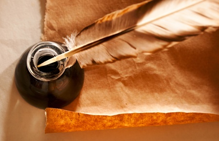 Feather and ink bottle on paper background の写真素材