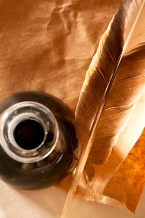 Feather and ink bottle on paper background の写真素材