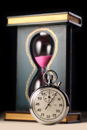 Stopwatch and sand watch on black background