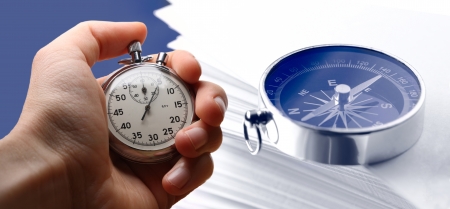 Hand holding stopwatch, stack of paper cards and compassの写真素材