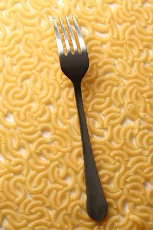 Short ribbed pasta tubes background with forkの写真素材
