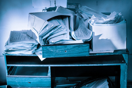 Messy workplace with table and stack of paperの写真素材