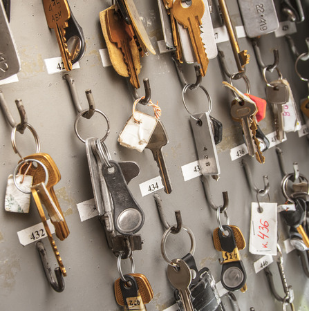 Office room keys with tags hanging on wooden boardの写真素材