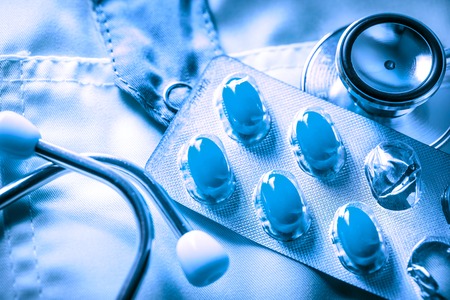 Stethoscope and pills on doctor's smock in toningの写真素材