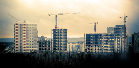 Many tall buildings under construction and cranesの写真素材