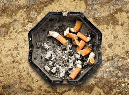 Black ashtray with ñigarette stubs in closeupの写真素材