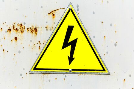 Old yellow sign with high voltage iconの写真素材