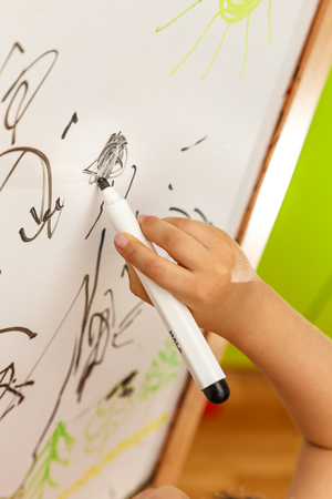 Child's hand drawing with marker on blackboardの写真素材