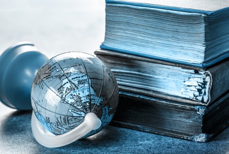 Pile of old books and globe in closeupの写真素材