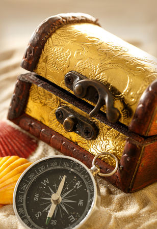 Treasure chest with seashells and compass on sandの写真素材