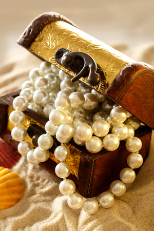 Treasure chest with seashells and pearl on sandの写真素材