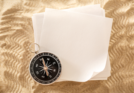 Blank sheets of paper with compass on sandの写真素材
