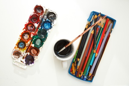 Watercolor paints in box with brush and box of pencils