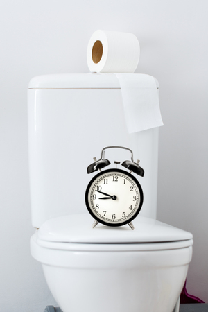 Hygienic paper on white toilet tank and alarm clockの写真素材